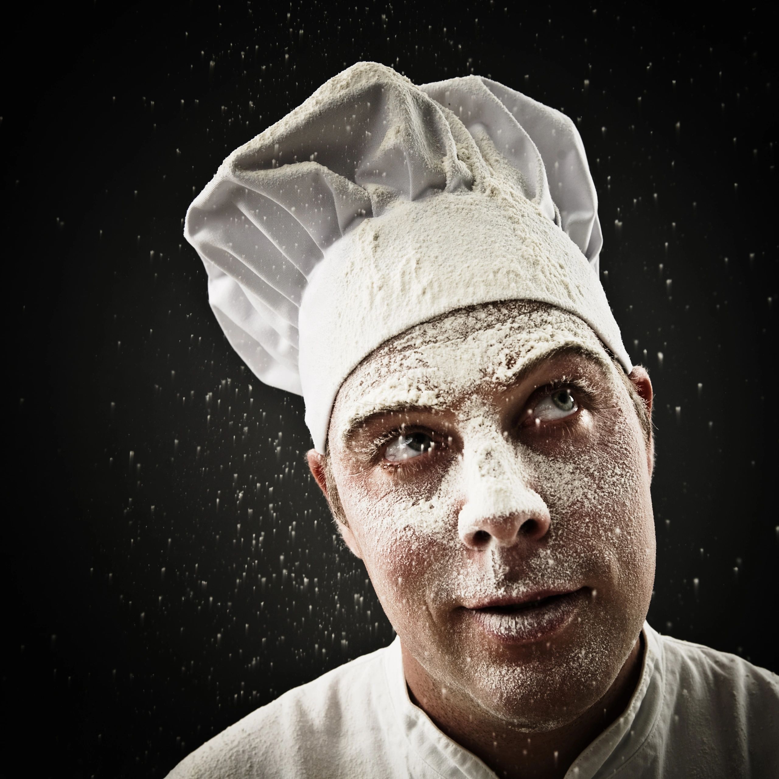 Chef being showered with flour in a dramatic kitchen portrait