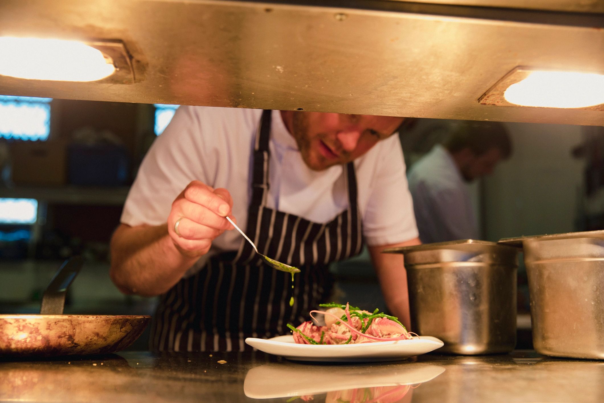 Chef plating a refined seafood dish in a professional kitchen